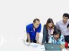 A group of people sitting around a laptop computer.