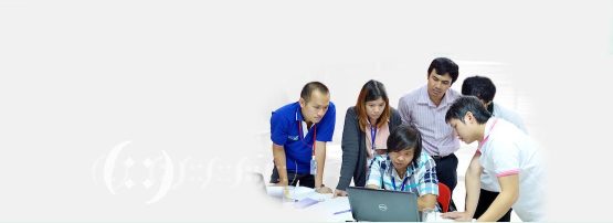 A group of people sitting around a laptop computer.