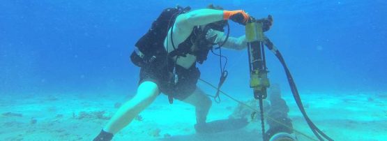 A US Navy Construction Electrician installs cable stabilisers ay Kwajeilen, 2014