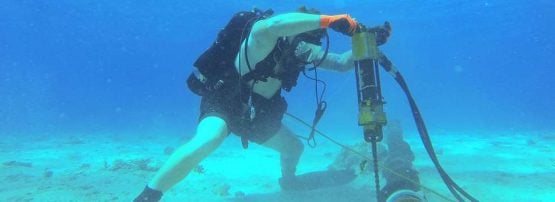 A US Navy Construction Electrician installs cable stabilisers ay Kwajeilen, 2014