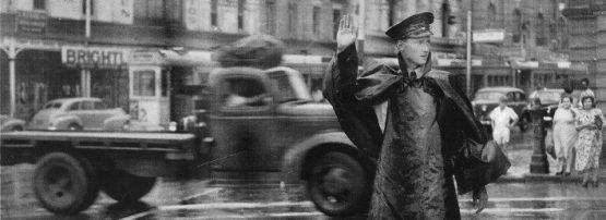 A policeman directs traffic on the corner of Queen and William Street, Brisbane, during very inclement weather, December 19, 1954.
