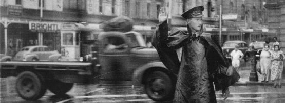 A policeman directs traffic on the corner of Queen and William Street, Brisbane, during very inclement weather, December 19, 1954.